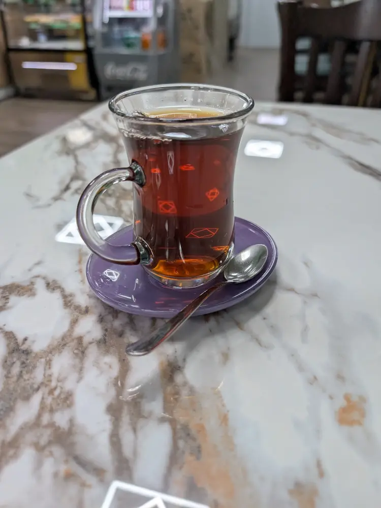 Glass of Turkish tea on a lilac saucer on a marble table