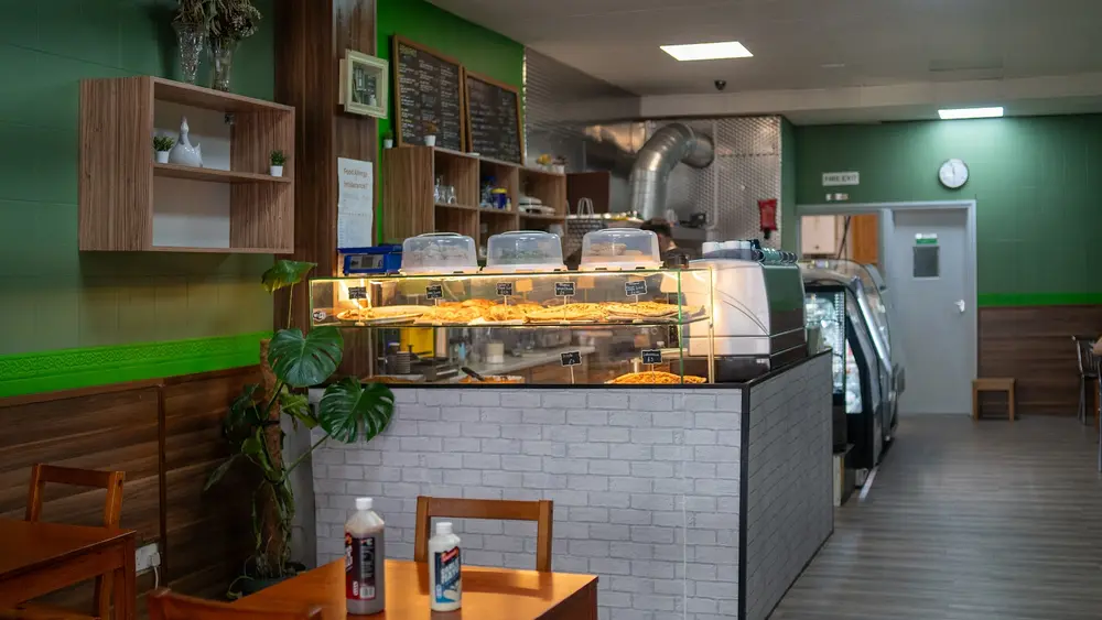 Inside Eleventh Kitchen: green walls, wooden tables and a lit counter of fresh gözleme